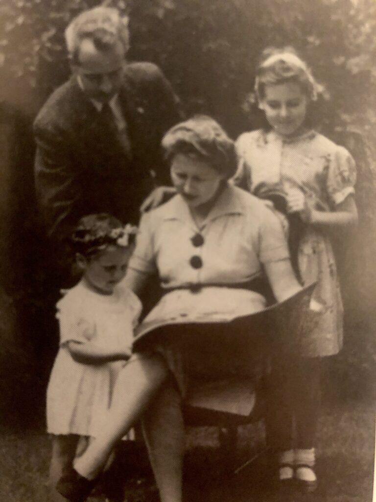 Posing to look at a book together, an oddity of the time, and perhaps still today where the photograph captures a “real” moment, that is anything but reflective of who they are. A slice of a pretend life, like a piece of cake lacking flour and sugar. Family looking at book in garden of 38 Keele Street. Elsie McEwen, centre, left to right; Gwendolyn (age three),Alick McEwen, and Carol. ??Photo by Carol Wilson.